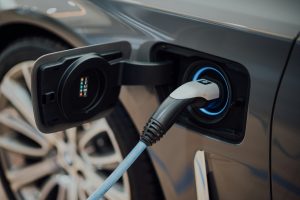 close up image of an electric car plugged in, used to represent one of the ways you can invest in decarbonisation