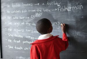 young child writing on chalk board in classroom