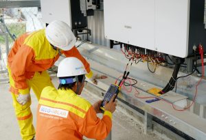 two people connecting solar power to the side of a building